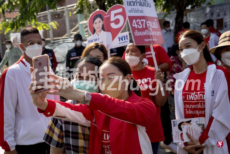 泰国前首相达信小女儿佩通坦（中）昨日首次在曼谷亮相，为参与地方选举的为泰党候选人催票并与选民玩自拍。（法新社）